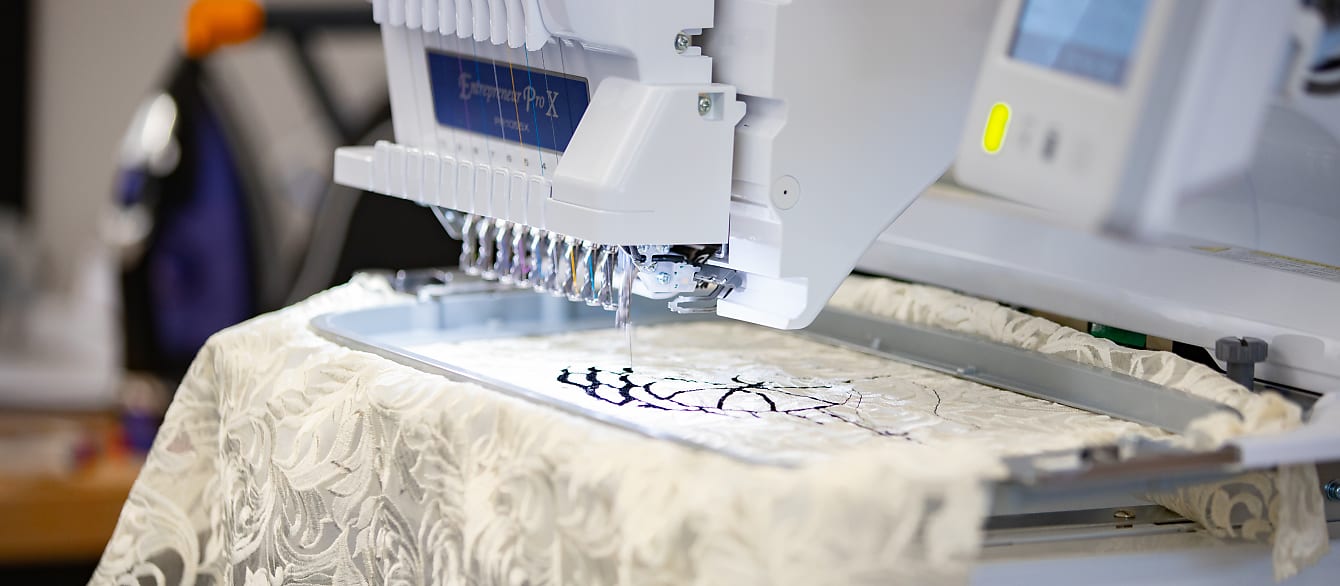 Close-up of the Create Space embroidery machine stitching in black thread on a piece of lace fabric