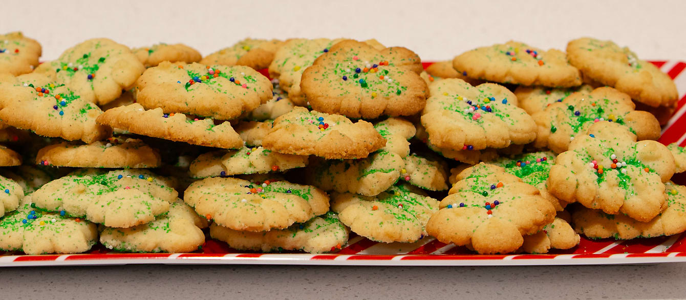 Close-up of a tray of Christmas tree Spritz cookies, decorated with festive sprinkles