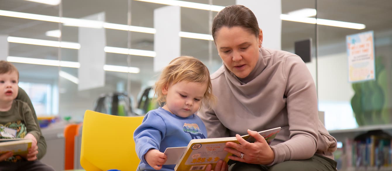 a toddler and a mother hold a board book together.