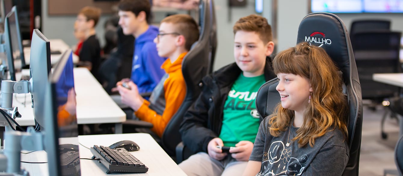 A line of teenagers stare intently at computer screens while playing Super Smash Brothers