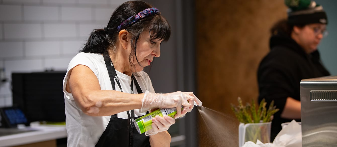 A librarian sprays a pan with avocado oil to prepare to air fry asparagus.