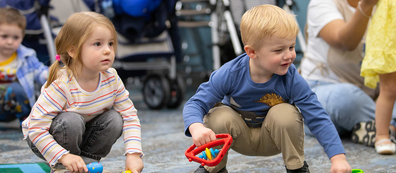 A preschool age little boy and little girl with blond hair look at the hand-held instruments that are available to them