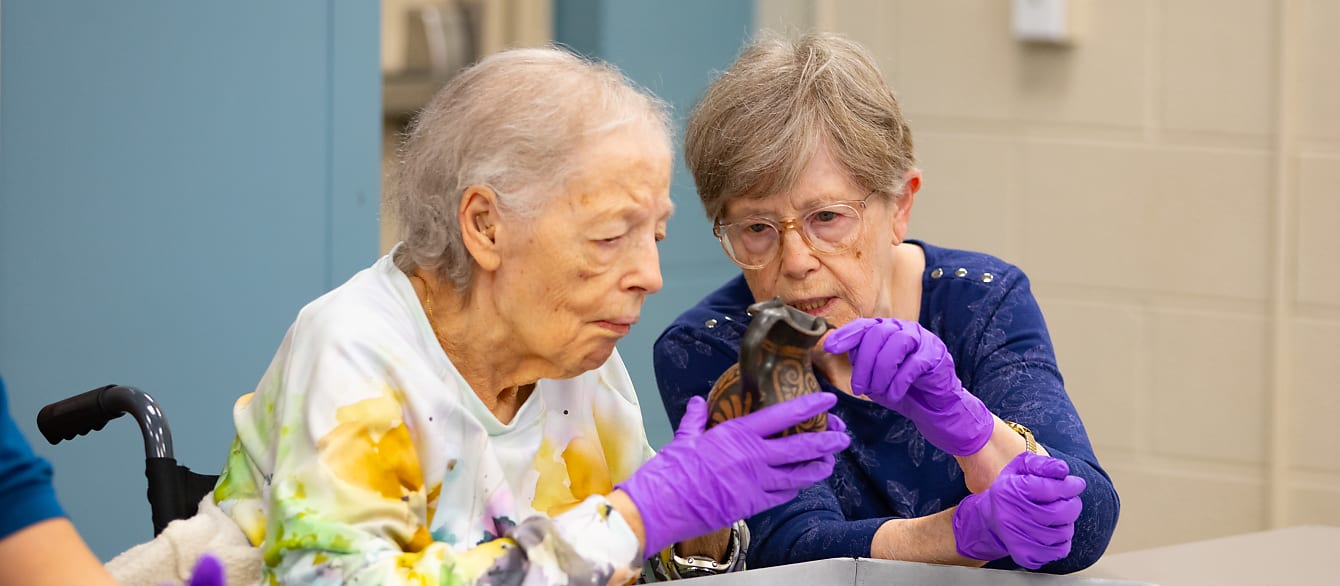 Two senior women look at a jug from the Cleveland Museum of Art