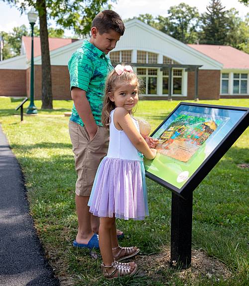 Image of Brother and Sister looking at the StoryWalk&reg; Book